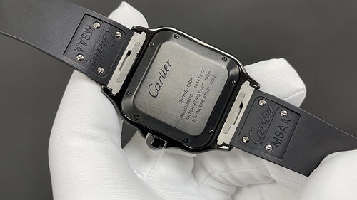 Cartier watch case with clasp and engraved back, black strap on white gloves.