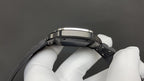 Cartier watch underside with black strap and metal case, held by white gloves.