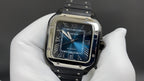 Cartier Santos watch with blue dial, Roman numerals, and metal bezel on strap.
