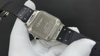 Cartier watch caseback with engraved markings and black leather strap on hand.