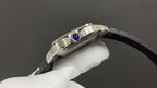 Cartier watch front-right view with blue crown detail and black leather strap.
