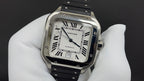 Cartier watch with silver frame, Roman numeral dial, and black leather strap detail.