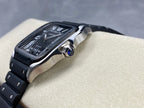 Cartier wristwatch angled view showing black dial, steel case, and silver-tone crown on black bracelet.