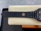 Dark leather-style wristwatch strap with metal buckle and round stamped logo