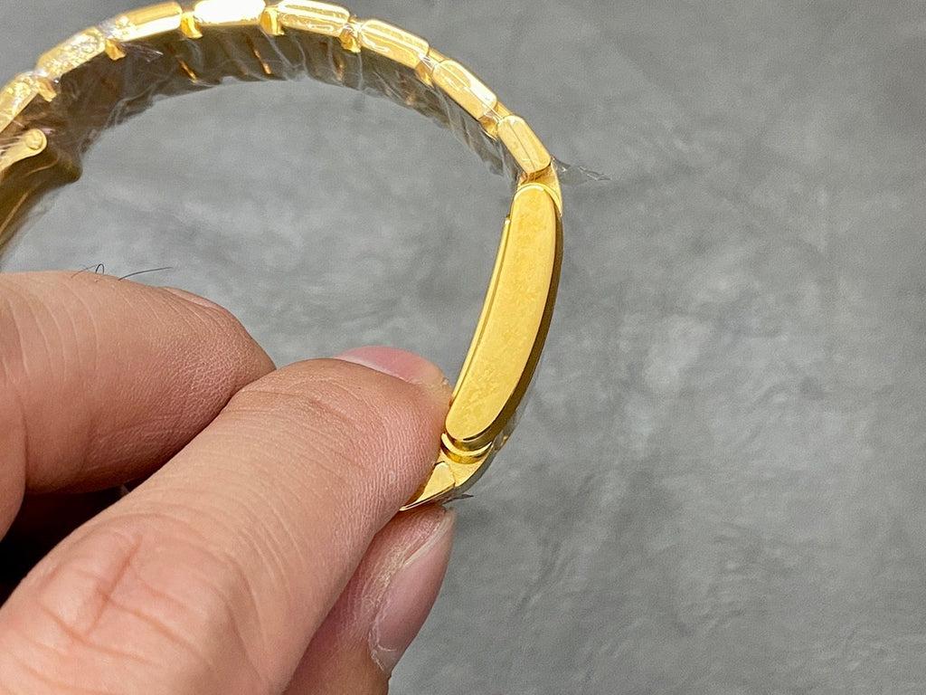 Gold-tone watch case with linked bracelet held in hand