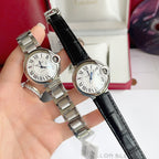 Two wristwatches held: steel bracelet watch and black leather strap watch with white dial.