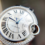Cartier Ballon Bleu watch close-up: white dial, blue hands, diamond-studded bezel
