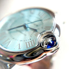 Cartier Ballon Bleu watch dial with blue hands and silver crown, close-up