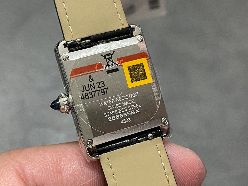 Cartier watch case back with cream strap, black markings, and visible water resistance text