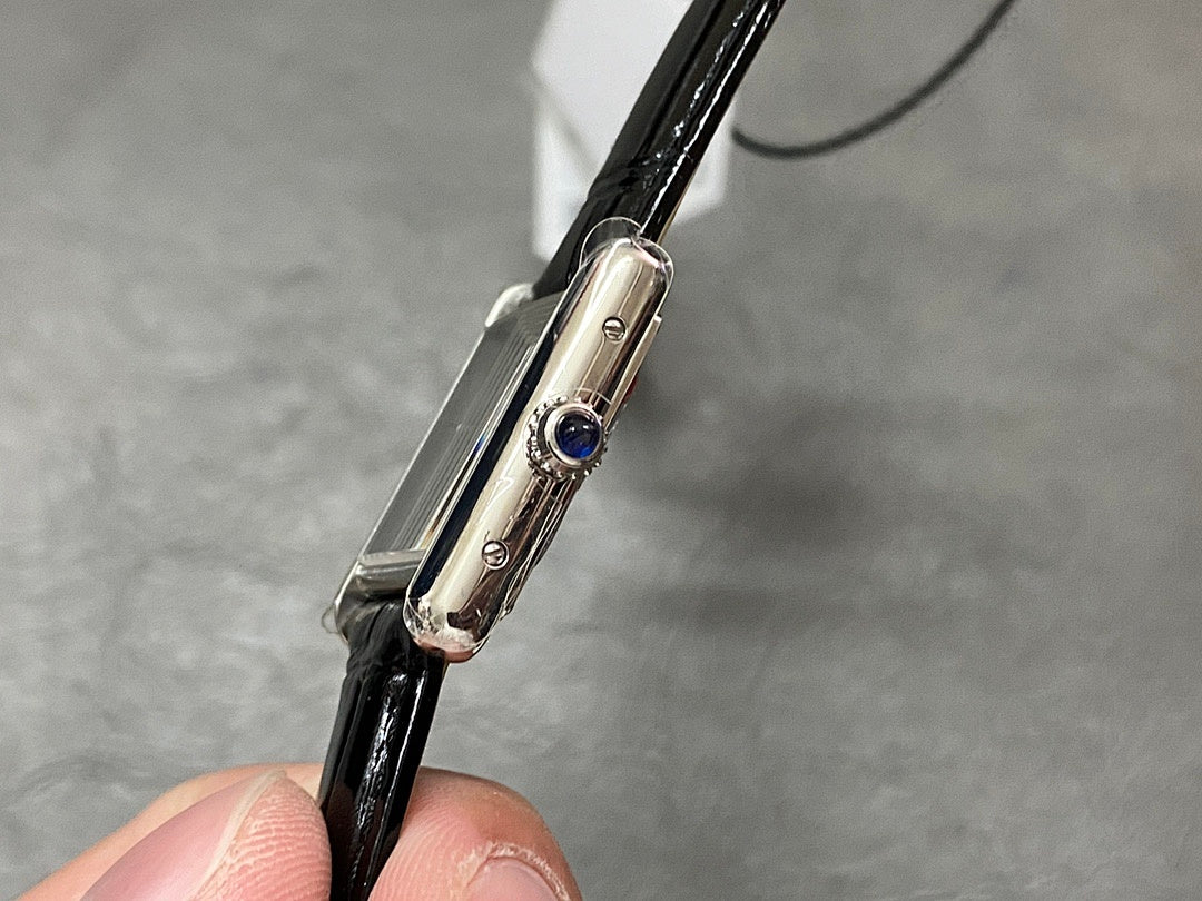 Cartier watch side profile with silver case, crown with blue gem, and black leather strap