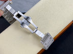 Cartier watch bracelet with silver-tone links and buckle, shown from side on a beige cushion.