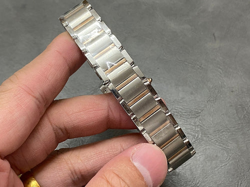 Silver metal bracelet links and clasp of a Cartier tank-style watch, held in hand