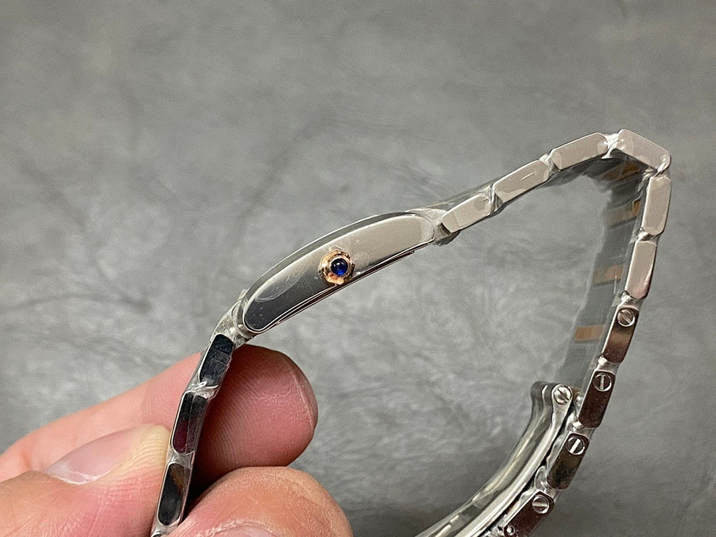 Cartier wristwatch with polished oval bezel, small blue gemstone detail, metal strap