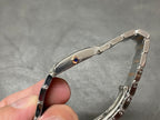 Cartier wristwatch with polished oval bezel, small blue gemstone detail, metal strap