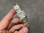 Cartier tank-style watch with silver Roman numeral dial and metal bracelet, angled view