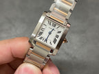 Cartier tank-style watch face with Roman numerals, blue hands, and silver metal bracelet
