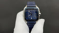 Cartier watch with blue dial, Roman numerals, and blue leather strap on white glove