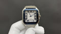 Cartier Santos-style watch with blue bezel, Roman numeral dial, stainless steel bracelet