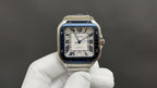 Cartier Santos-style watch with blue bezel, Roman numeral dial, stainless steel bracelet