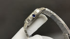 Cartier watch with steel bracelet, side view of case and blue gemstone crown