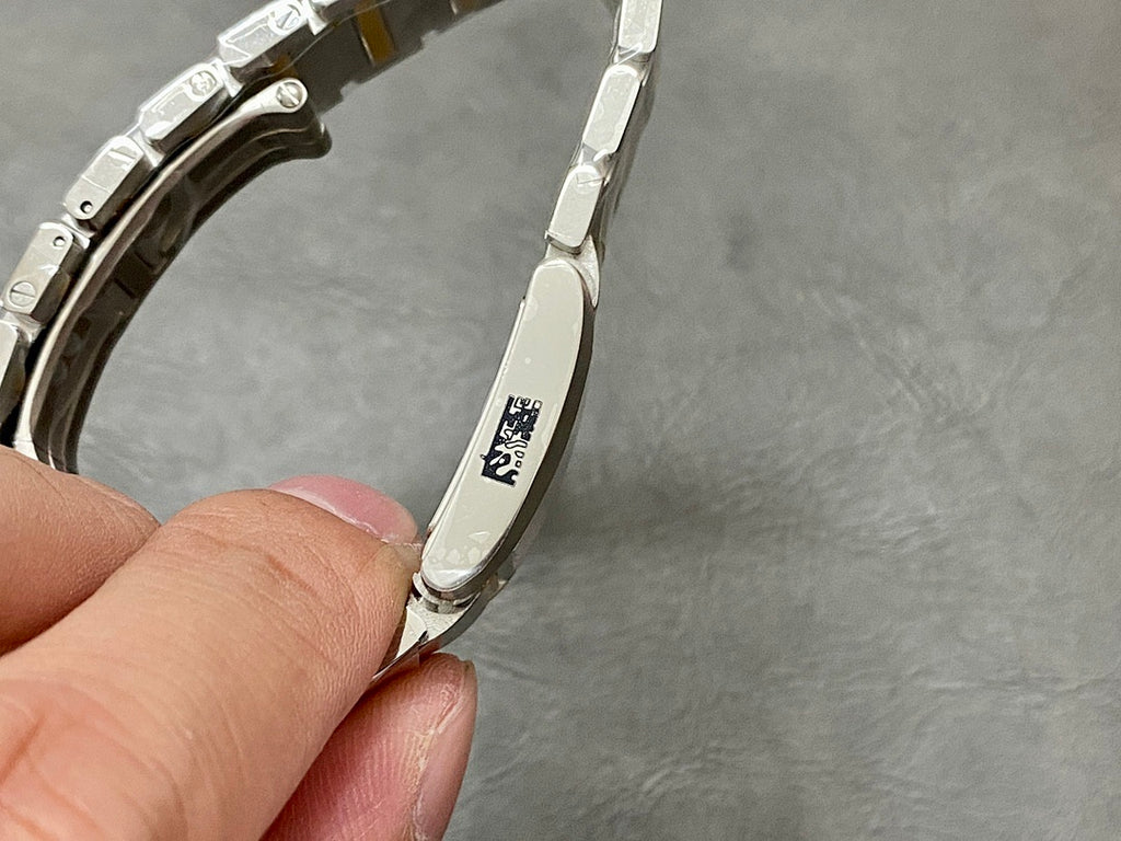 Two-tone wristwatch bracelet underside with engraved markings on metal link