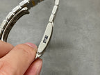 Two-tone wristwatch bracelet underside with engraved markings on metal link