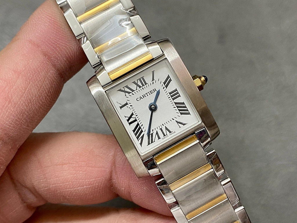Close-up two-tone wristwatch with white dial, Roman numerals, and blue-tinted hands