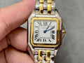 Cartier watch with gold bezel, silver-and-gold bracelet, roman numeral dial and blue hands