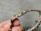 Cartier watch side view with gold crown detail and blue gemstone accent