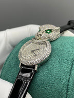 Cartier watch close-up with green cat head, emerald eyes, and round diamond dial
