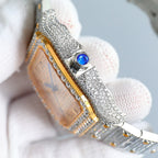 Rectangular gold dial watch with diamond bezel, blue gem detail, silver bracelet