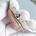 Cartier watch side view, jeweled silver bracelet, gold crown with blue gem detail.