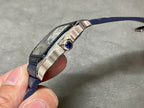Cartier watch side view with crown and sapphire-blue gemstone set in the bezel