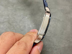 Silver-toned watch case profile with blue leather strap edge in close-up