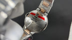 Cartier watch caseback with metal bracelet, red accent, and engraved text panel
