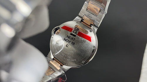 Cartier watch caseback with metal bracelet, red accent, and engraved text panel