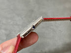 Cartier watch side profile with jeweled bezel, crown, and red leather strap