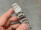 Stainless steel bracelet wristwatch with rectangular case held in a hand