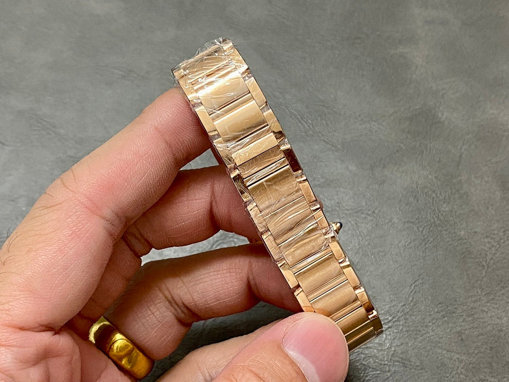 Gold-tone Cartier watch bracelet with polished links and clasp, held in hand