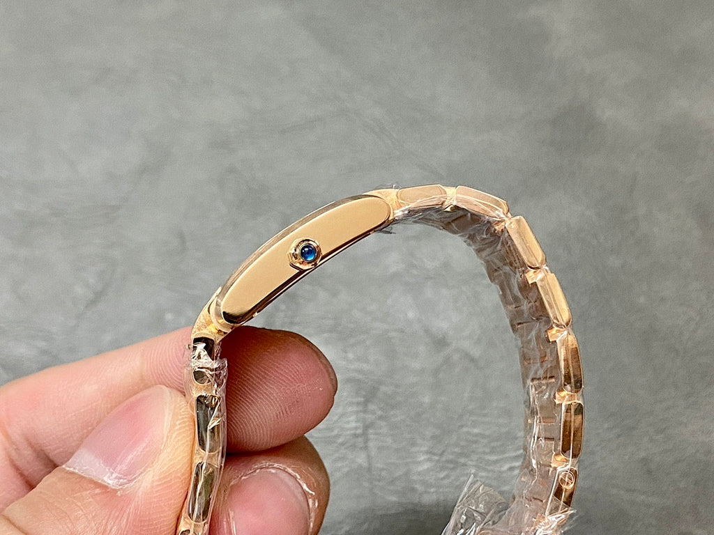 Gold-tone Cartier watch crown and bezel with blue jewel, close-up