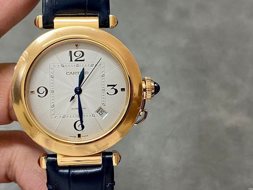 Cartier watch with gold-tone case, white dial, blue leather strap, side crowns visible