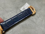 Blue leather watch strap with gold-tone clasp and keeper, shown from side