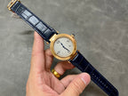 Cartier watch on blue leather strap with gold-tone case and white dial, held in hand