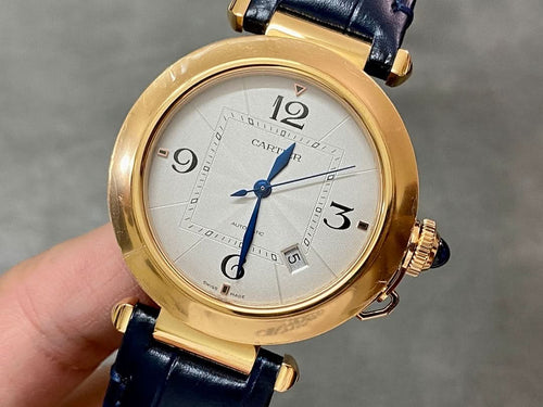 Cartier watch with gold-tone round case, white dial, blue leather strap, crown details