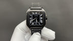 Cartier watch with black dial, Roman numerals, and black leather strap on silver-toned case.