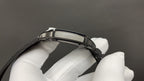 Cartier watch clasp and black leather strap with buckle holes, held by white glove.