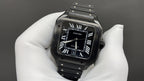 Cartier watch with black dial and Roman numerals, black leather strap, silver case detail.