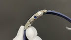 Silver watch case with crown and blue strap, wristwatch detail close-up