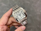Square silver Cartier wristwatch with Roman numeral dial, held in hand