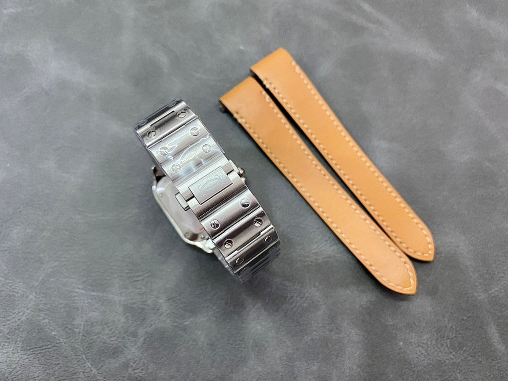Stainless steel watch bracelet with matching tan leather strap on gray surface